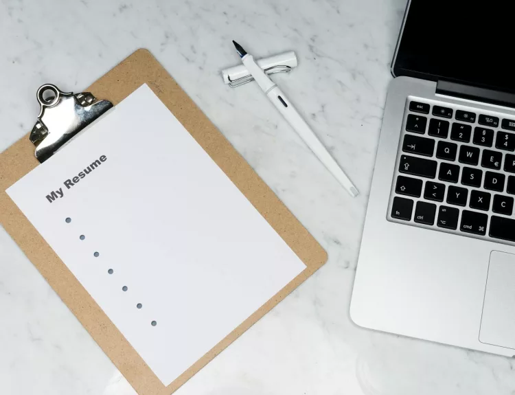 A Clipboard Near Pen and Laptop on a Marble Surface