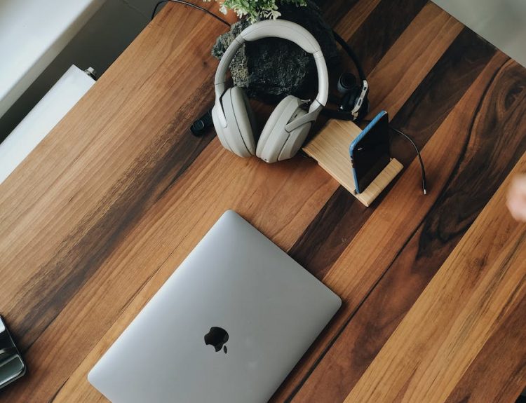 From above of modern laptop and devices placed on wooden table near window at daytime