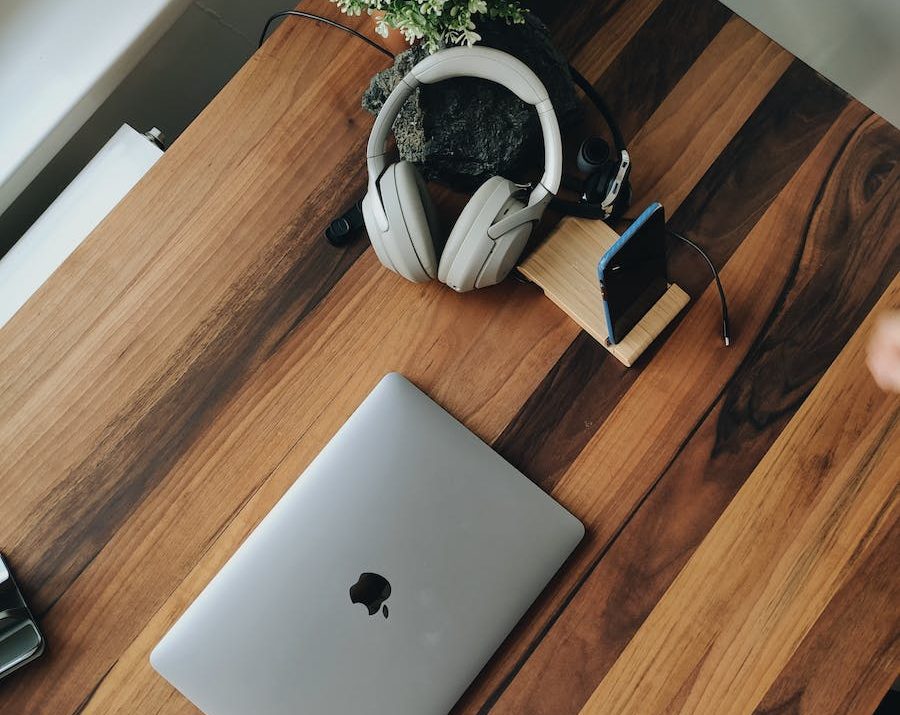 From above of modern laptop and devices placed on wooden table near window at daytime